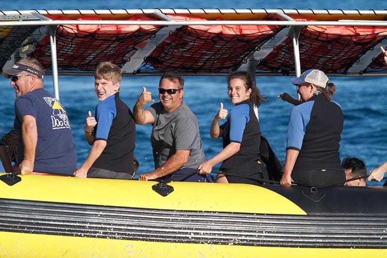 Happy group of snorkelers giving thumbs up sitting on the boat