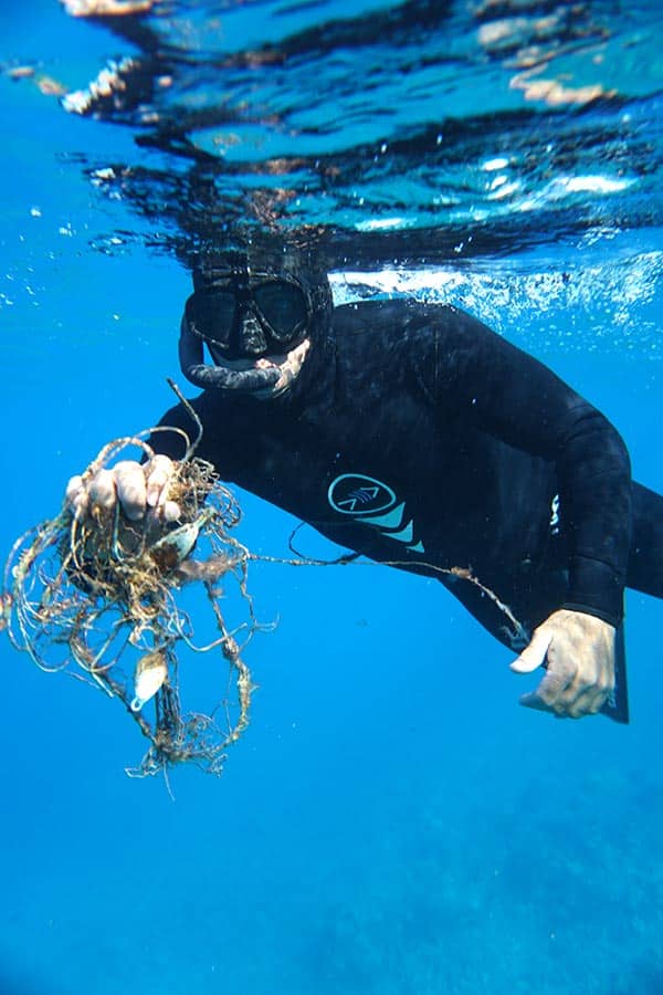 scuba diver holding trash underwater